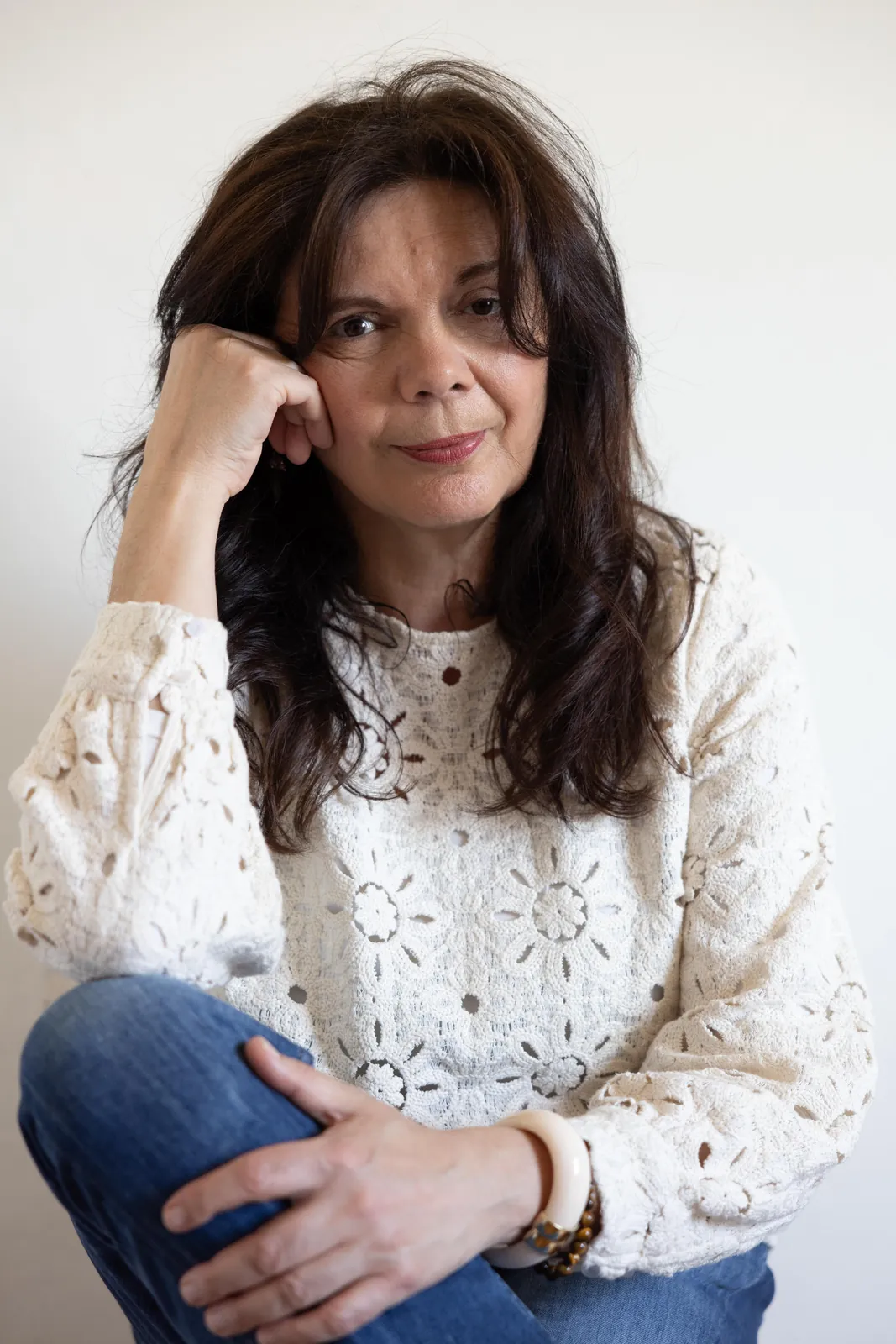 Laurence Perchard assise, en blouse de dentelle blanche, le menton posé sur la main