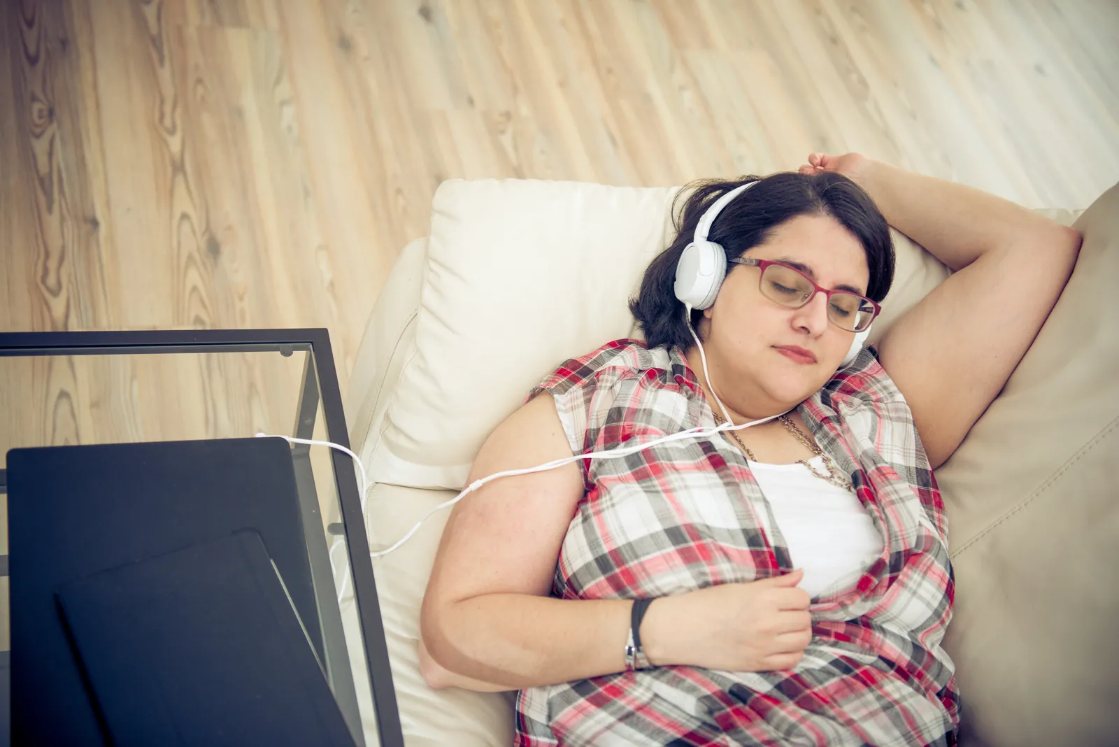Femme allongée dans un canapé, casque sur les oreilles, qui écoute l'enregistrement de sa séance
