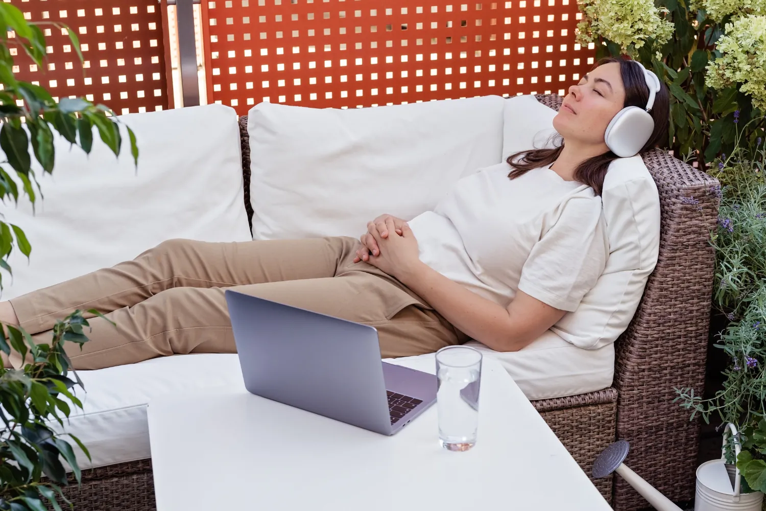 Femme allongée sur une terrasse, casque sur les oreilles, qui écoute l'enregistrement de sa séance