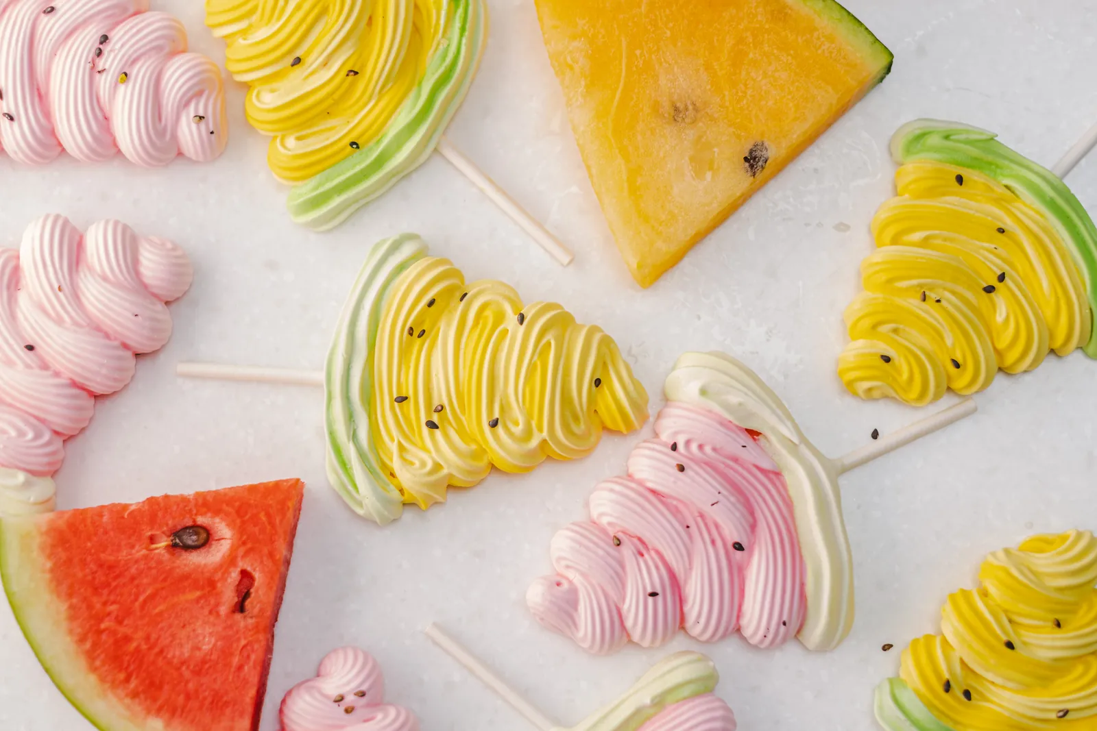 Sucettes et meringues colorées sur une table blanche